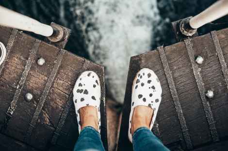 person on wooden bridge looking at body of water